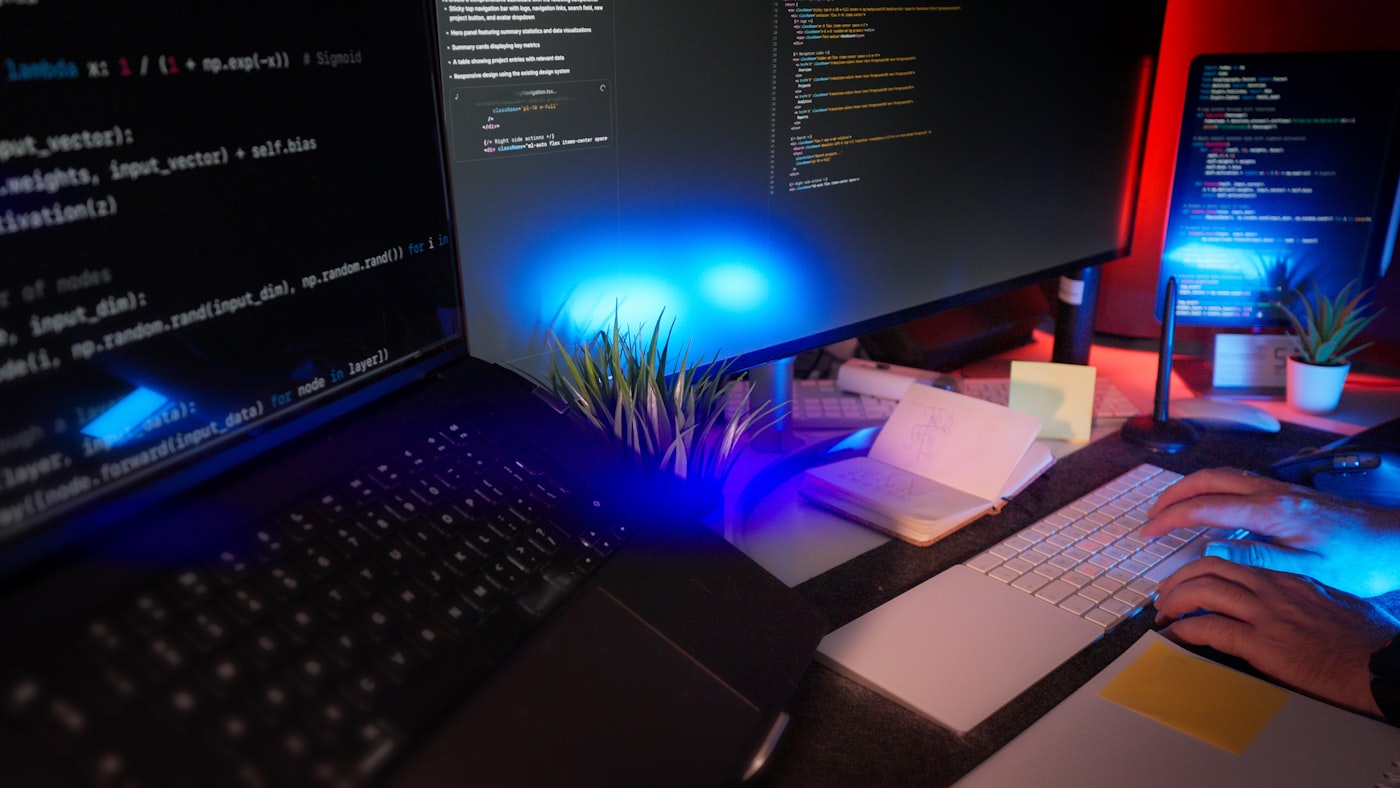 Puesto de trabajo con varias pantallas mostrando código y entorno de desarrollo.